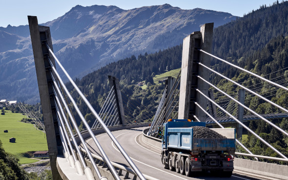 Ein Lastwagen fährt auf der Sunnibergbrücke in Richtung Berglandschaft. Das Bild vermittelt Aufbruchsstimmung.